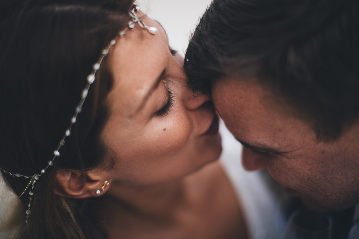 close up photograph of bride kissing grooms forehead