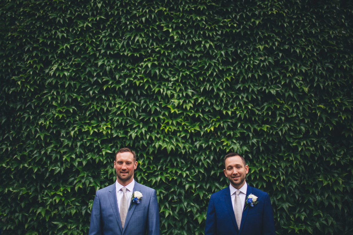 grooms against ivy backdrop