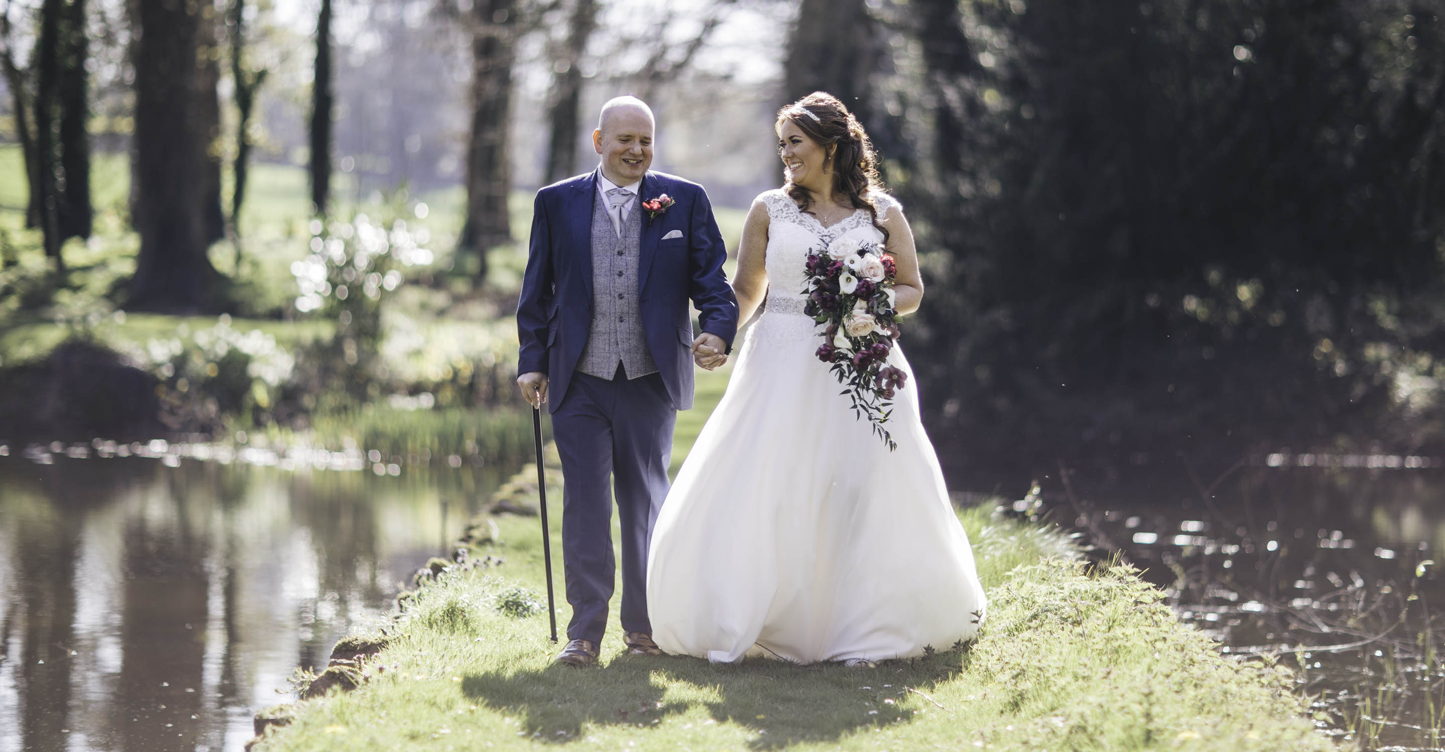 ailsa and jason walking through the woods back lit with sunshine