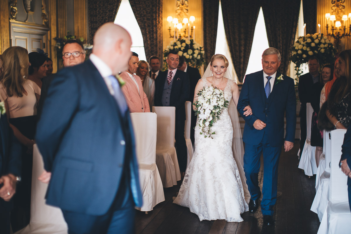 classic wedding photography of the bride arriving at the ceremony by walking down the aisle