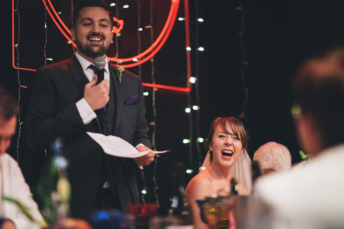 bride laughs at groom during the speeches at band on the wall