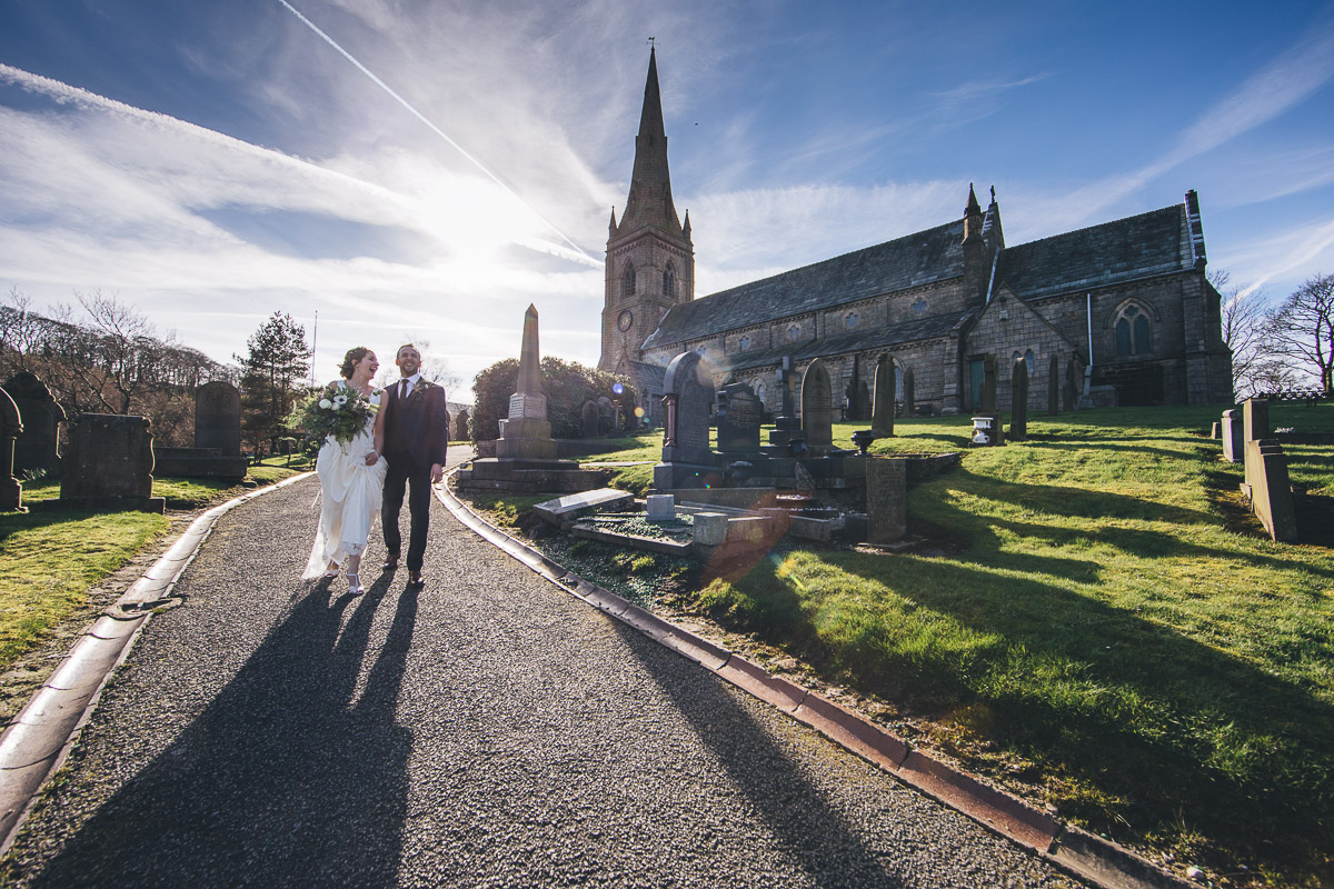 Bride and groom walking away fro mthe church Blue skies Clouds Churchyard