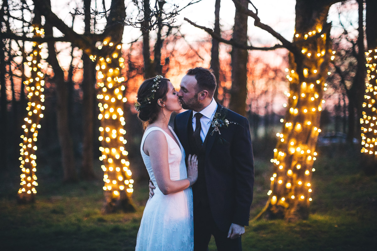 Bride and Groom Kiss Outside Trees Fairylights Woodland