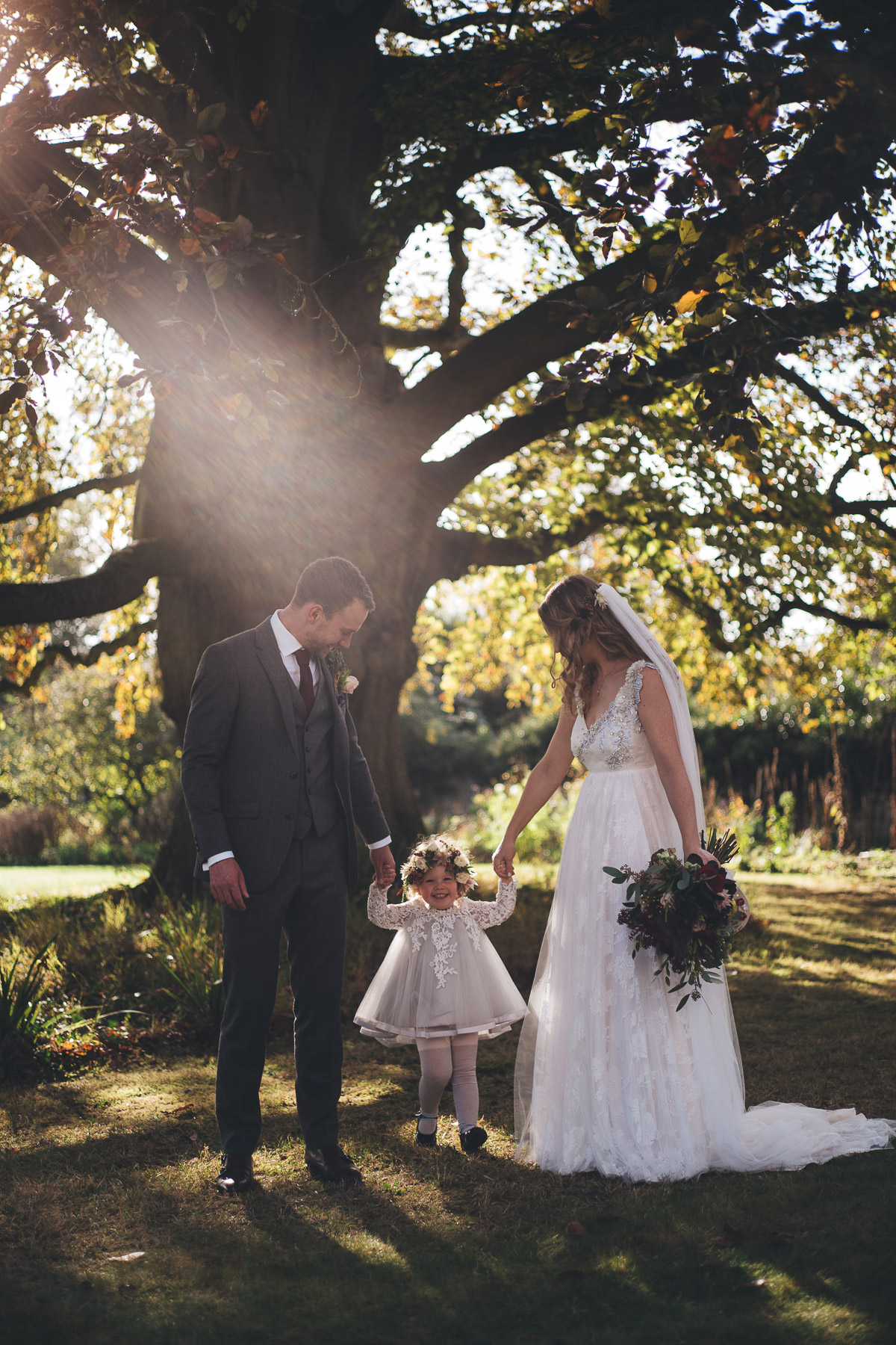 portrait of newly weds with little girl in back lit sunshine