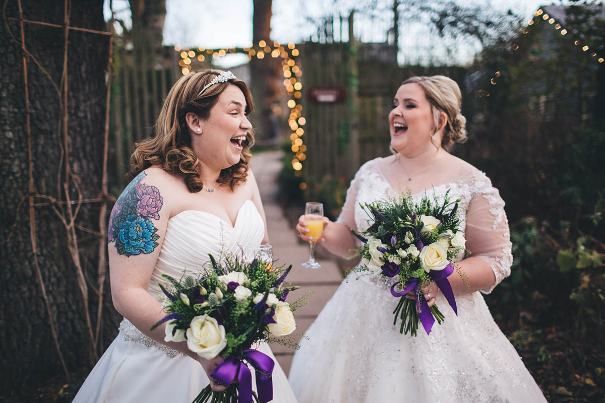 gay marriage two brides laughing in a naturally happy moment after their wedding ceremony
