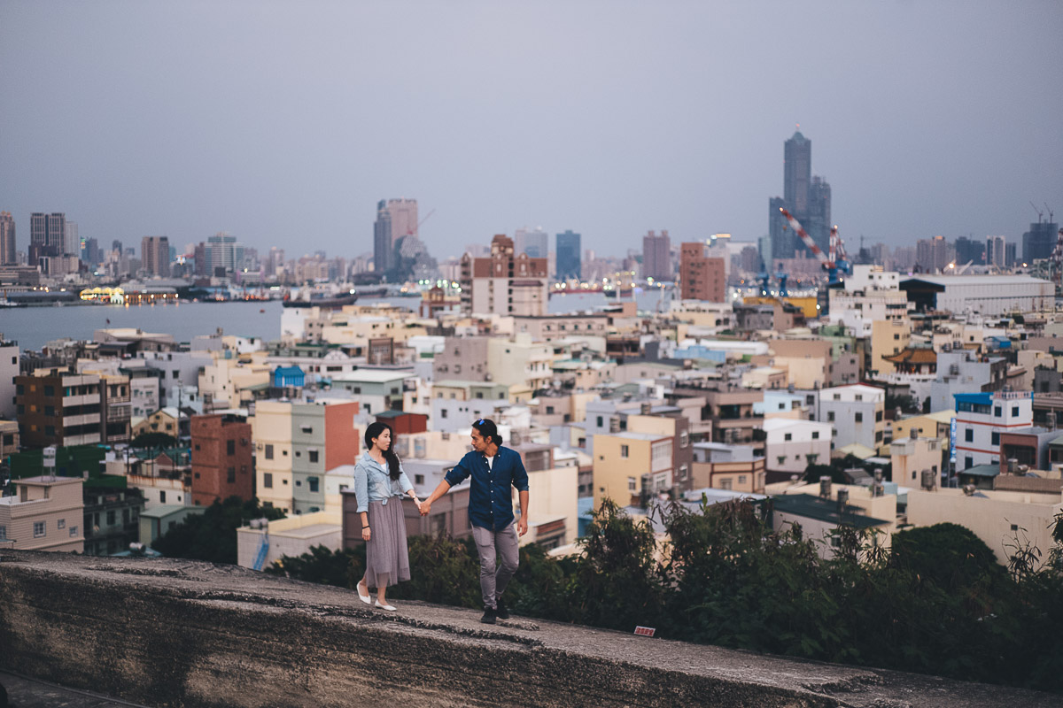 couples walking on a wall with kaohsiung in the background
