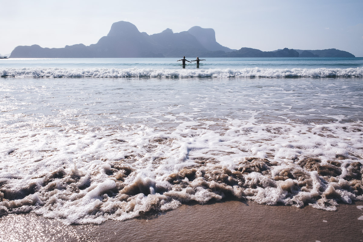 couple with arms stretched out as the play in the waves
