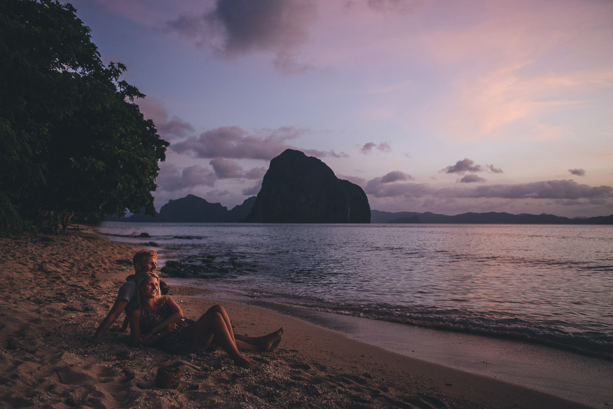 couple sat down on the beach at sunset
