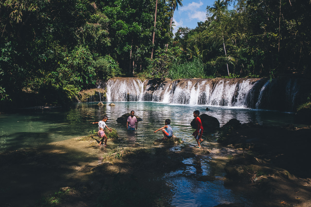 children playing by beautiful waterfall in siquijor