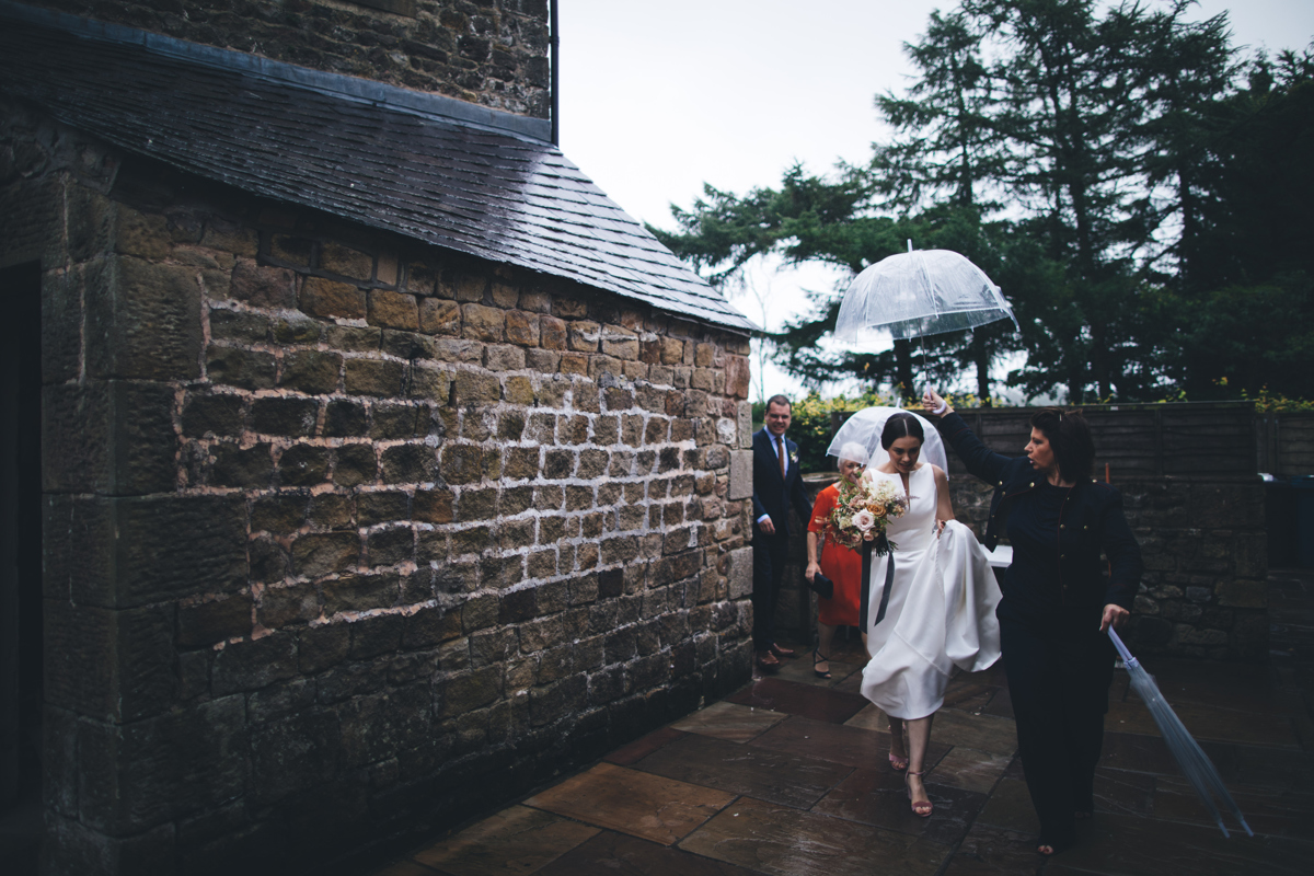 Bride heading outside under an umbrella