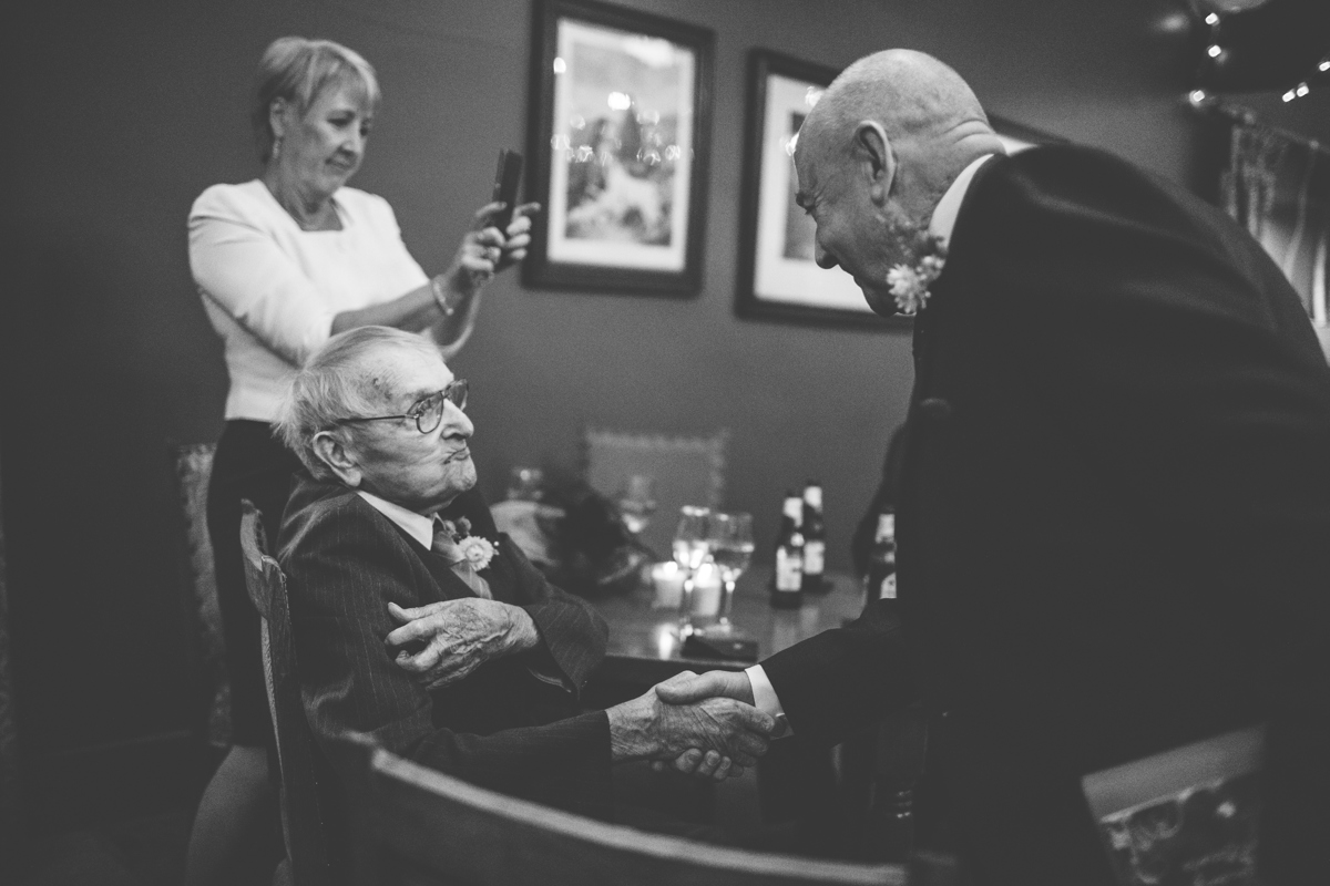 Seated elderly man shaking hands with another man