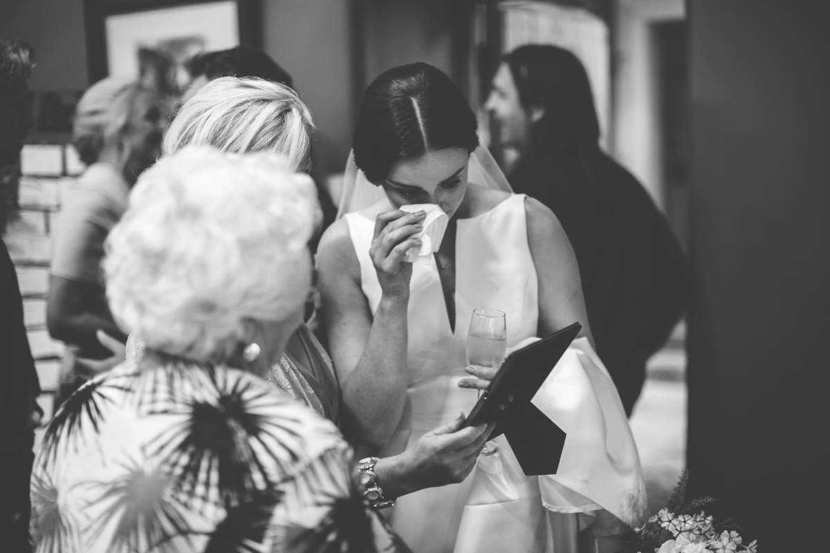 Bride looking at a picture holding a tissue to her eye