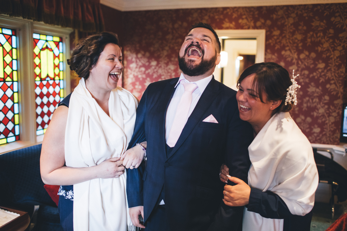 Groom laughing with his bridesmaids