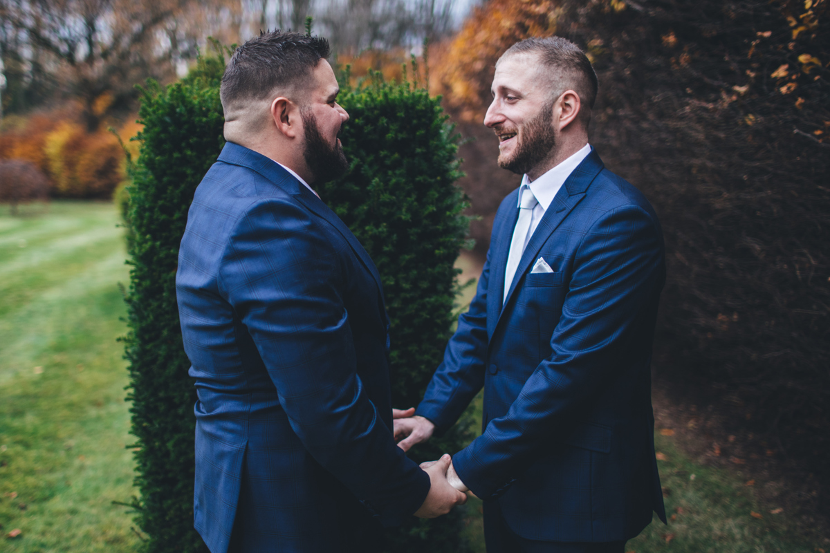 Two grooms holding hands after seeing each other for the first timeon their wedding day