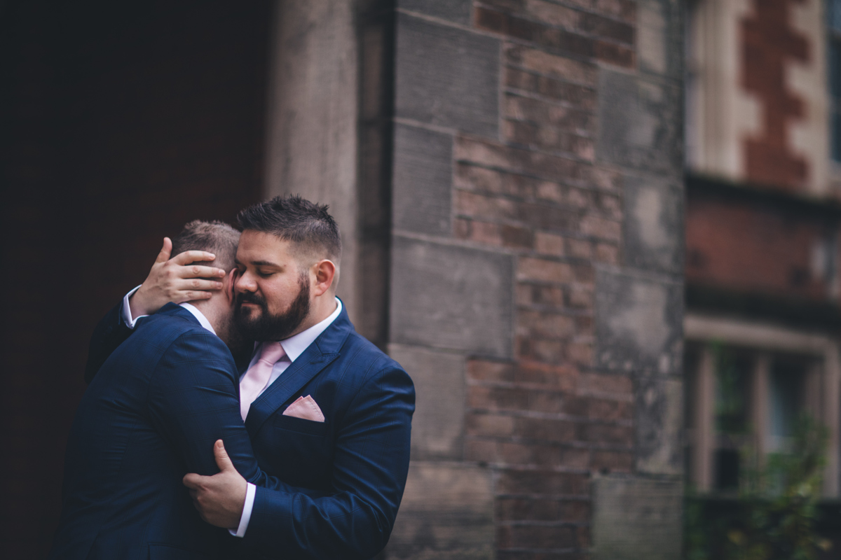 Two grooms embracing with their eyes closed
