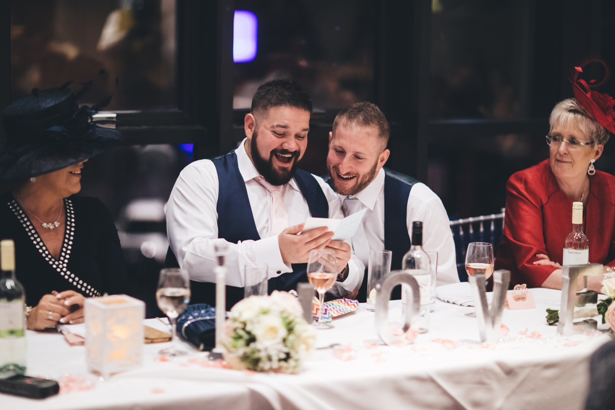 Two grooms looking at a card, laughing