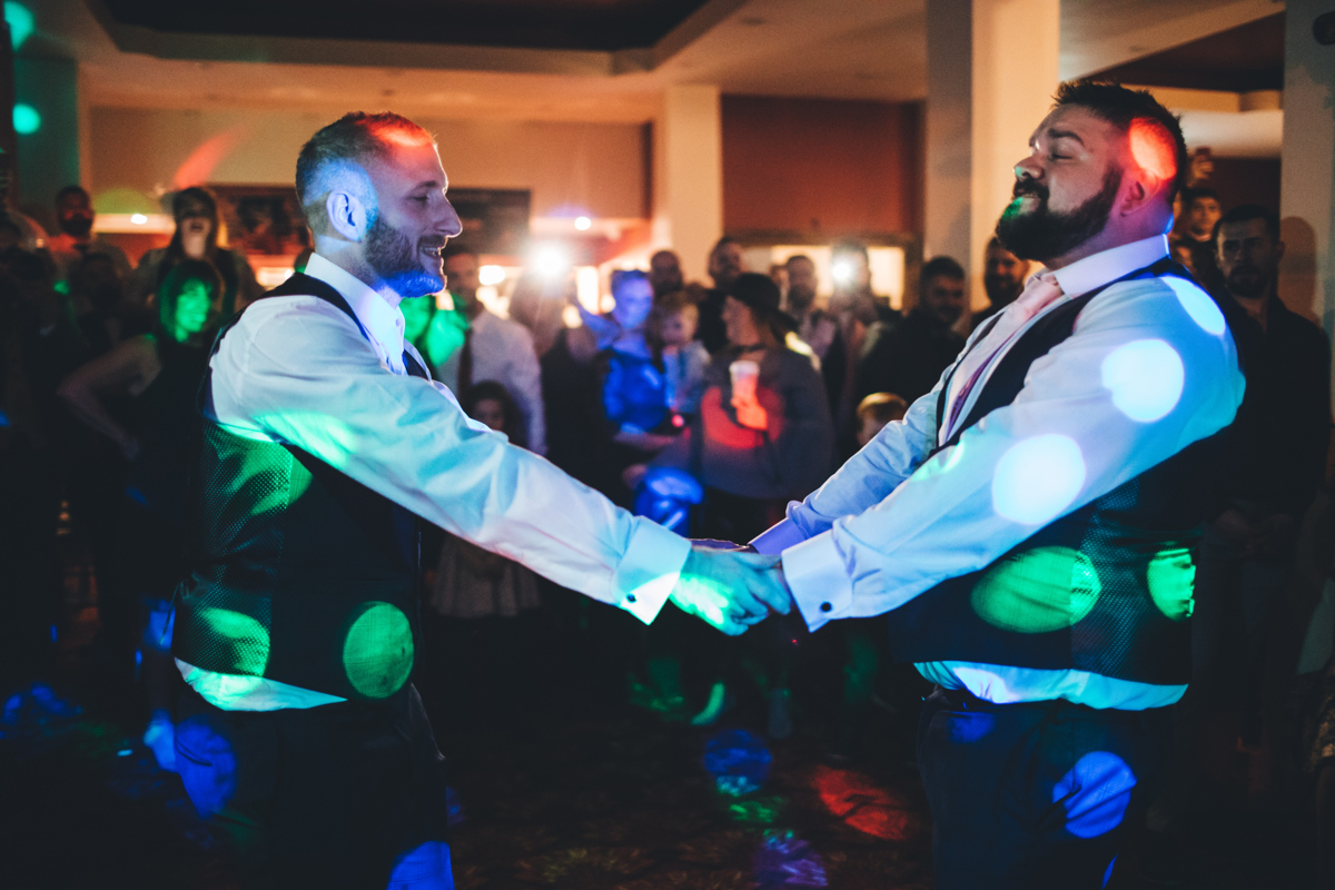 Two grooms holding hands on the dancefloor during their first dance