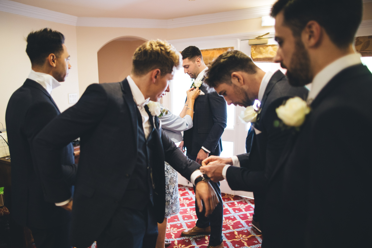Groom and groomsmen putting final touches to their outfits