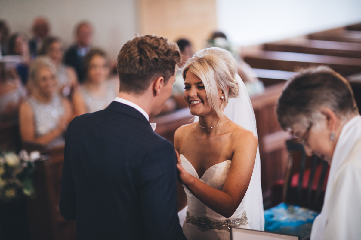 Bride and Groom together for the first time at the front of the church smiling at one another