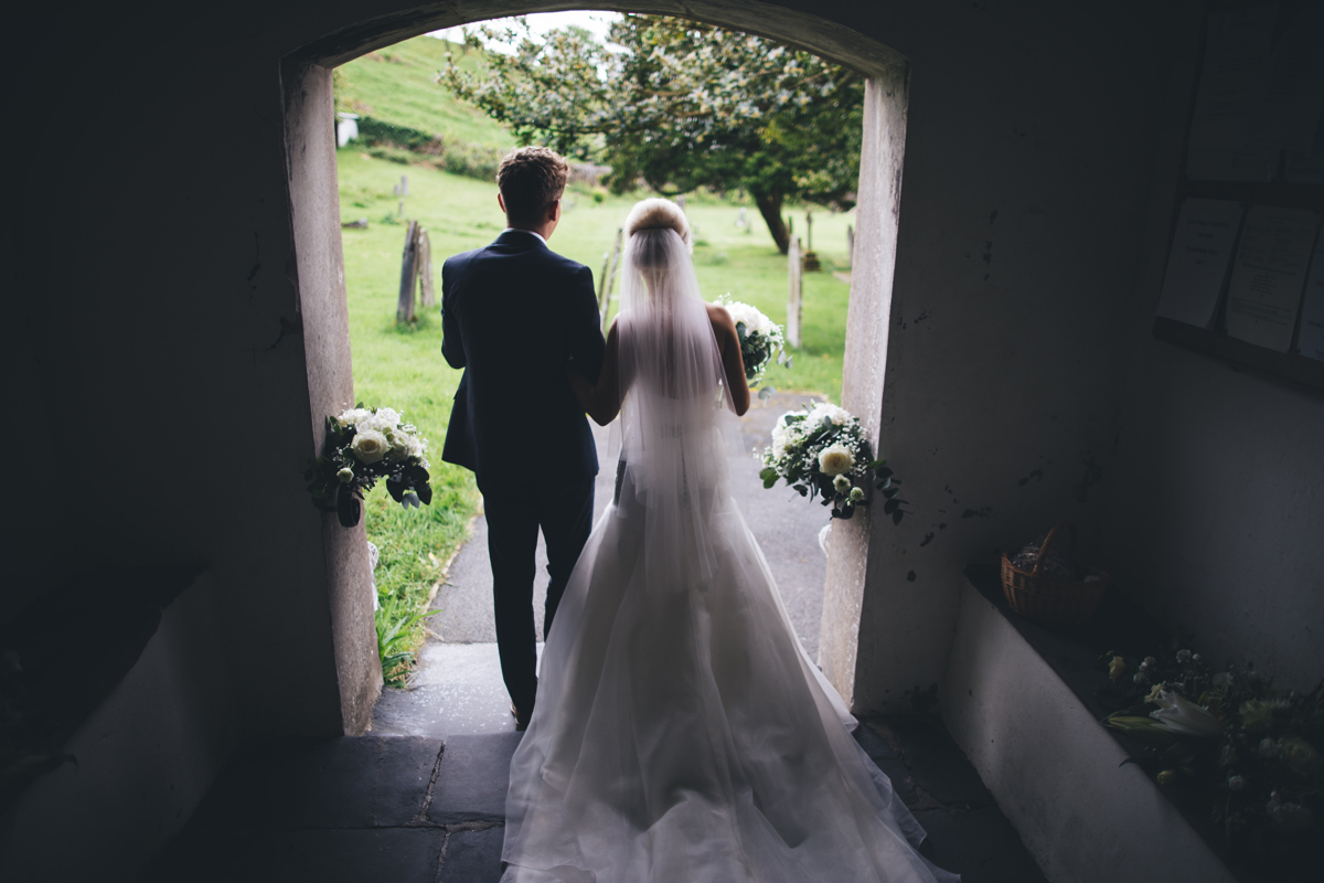Picture of the Bride and Groom from behind as the walk out of the church arm in arm