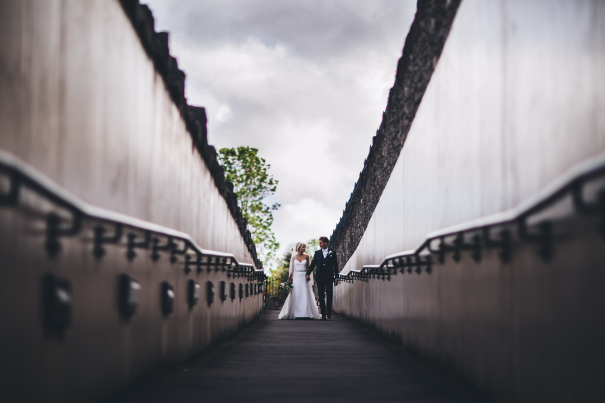 Bride and Groom in the distance walking down a path towards the camera with handrails on either side of the path