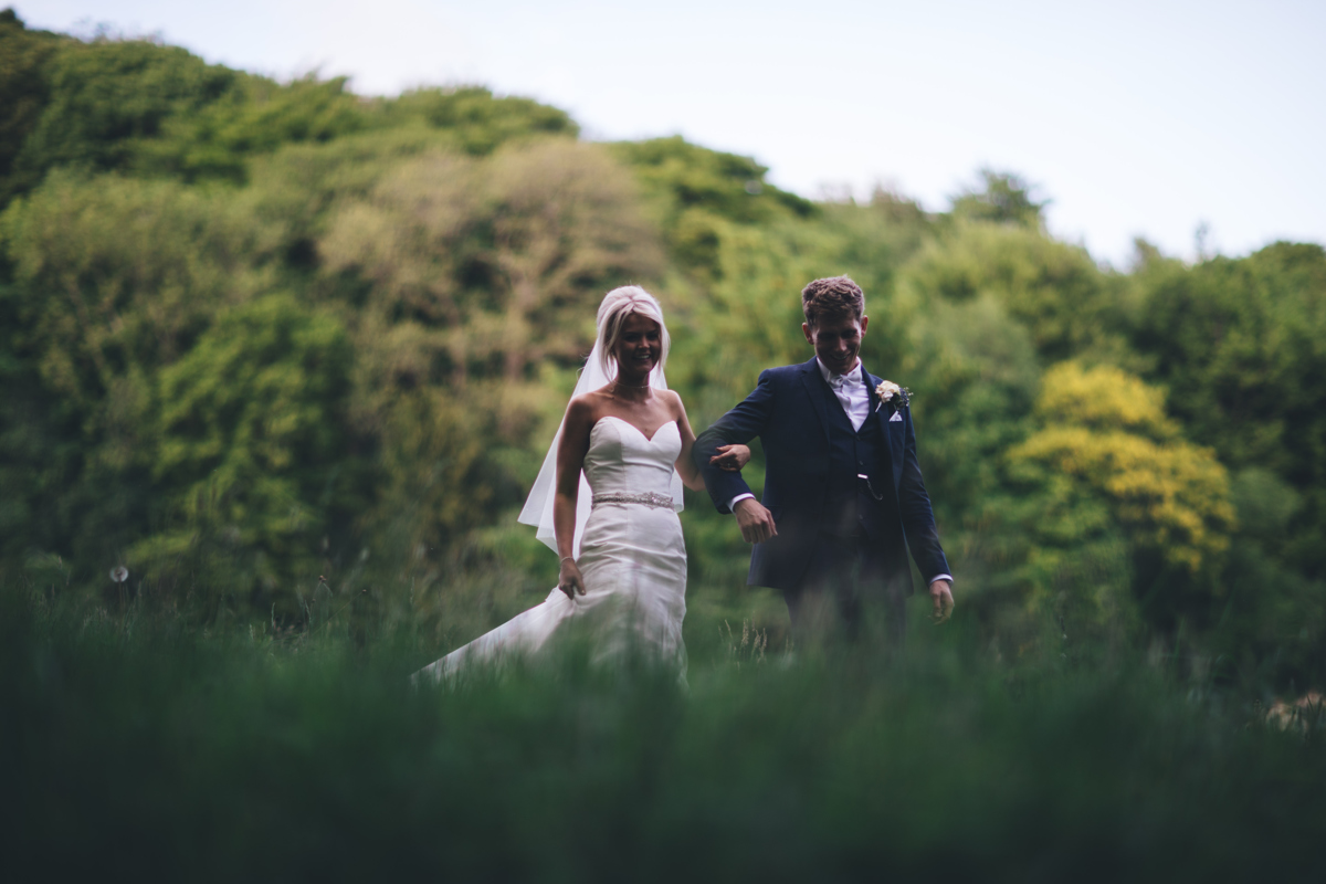 Bride and Groom walking through green woodland arm in arm