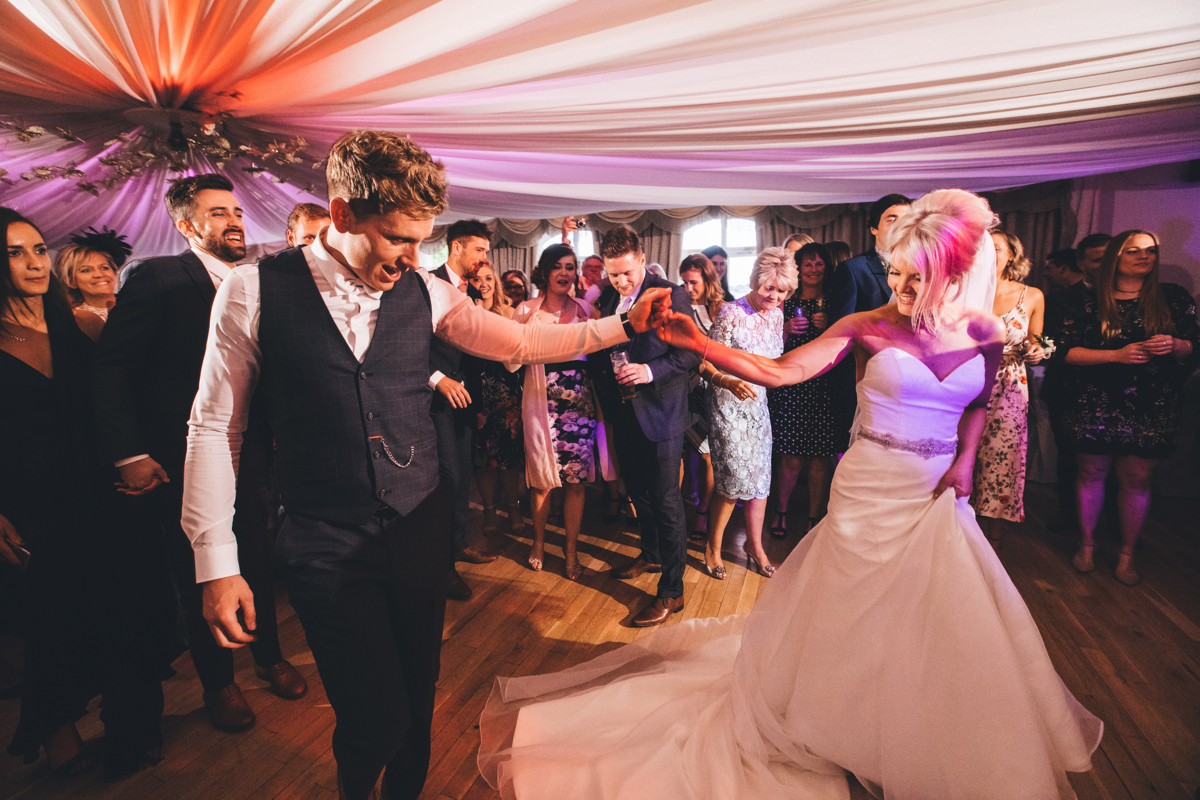 Bride and Groom walking out onto the dancefloor holding hands about to start their first dance