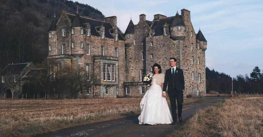 Bride and Groom hand in hand in front of Castle Menzies