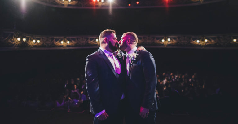 Two grooms on stage at Crewe Lyceum Theatre during their wedding service