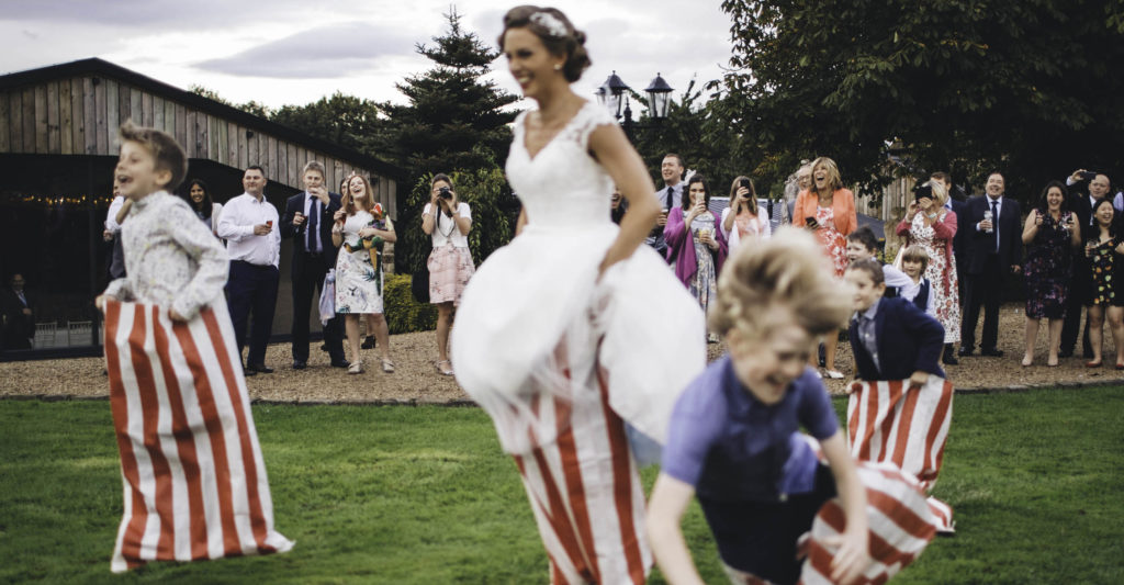 Bride and children jumping during a sack race