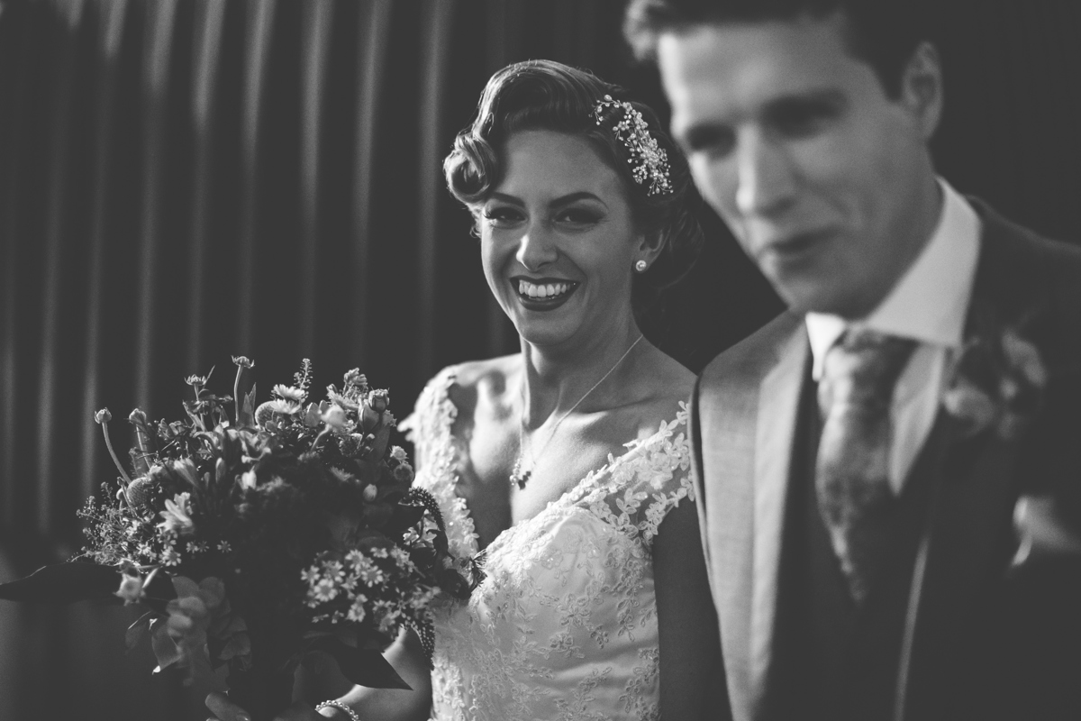 Bride holding a bouquet smiling with Groom out of focus