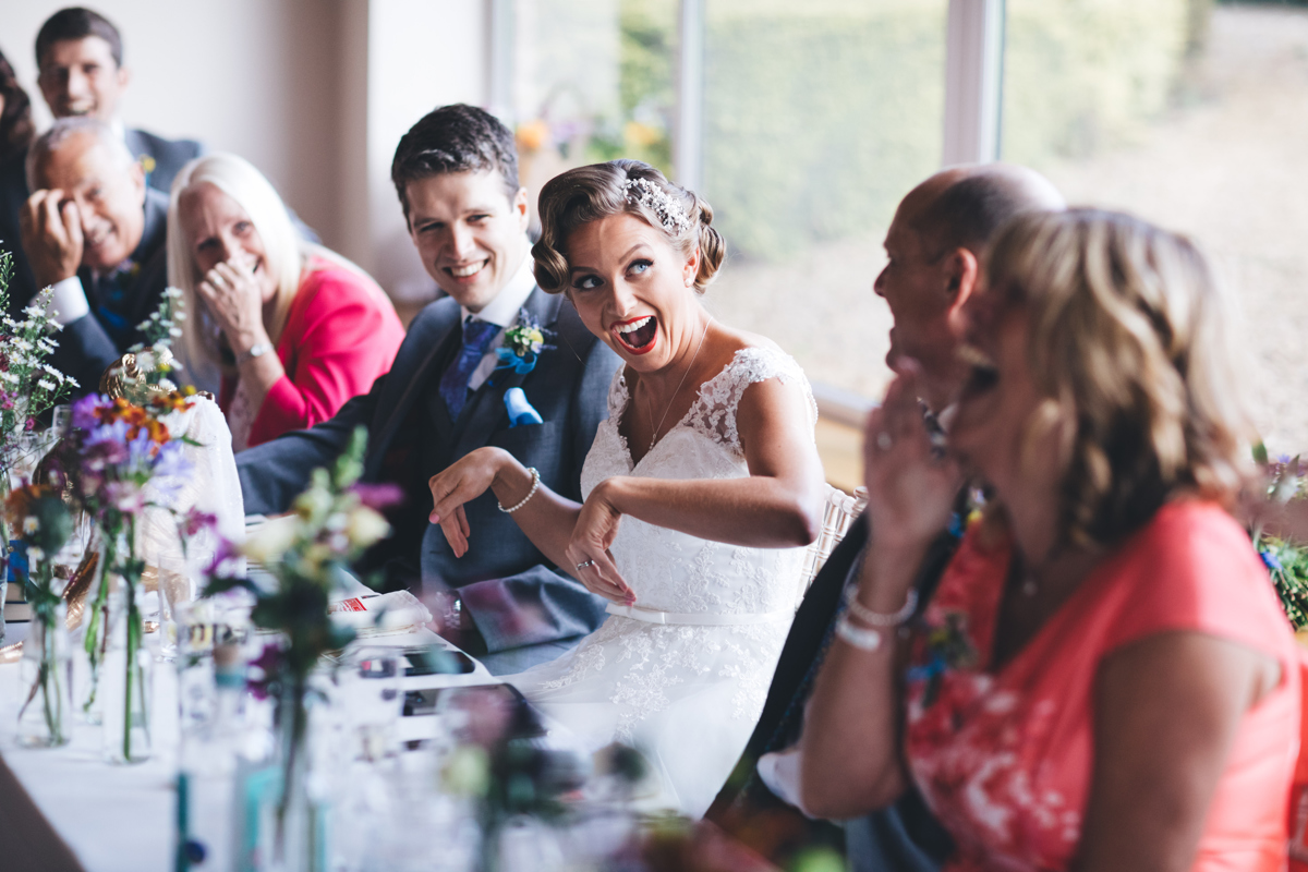 Bride doing dinosaur hand gesture with family looking on and laughing