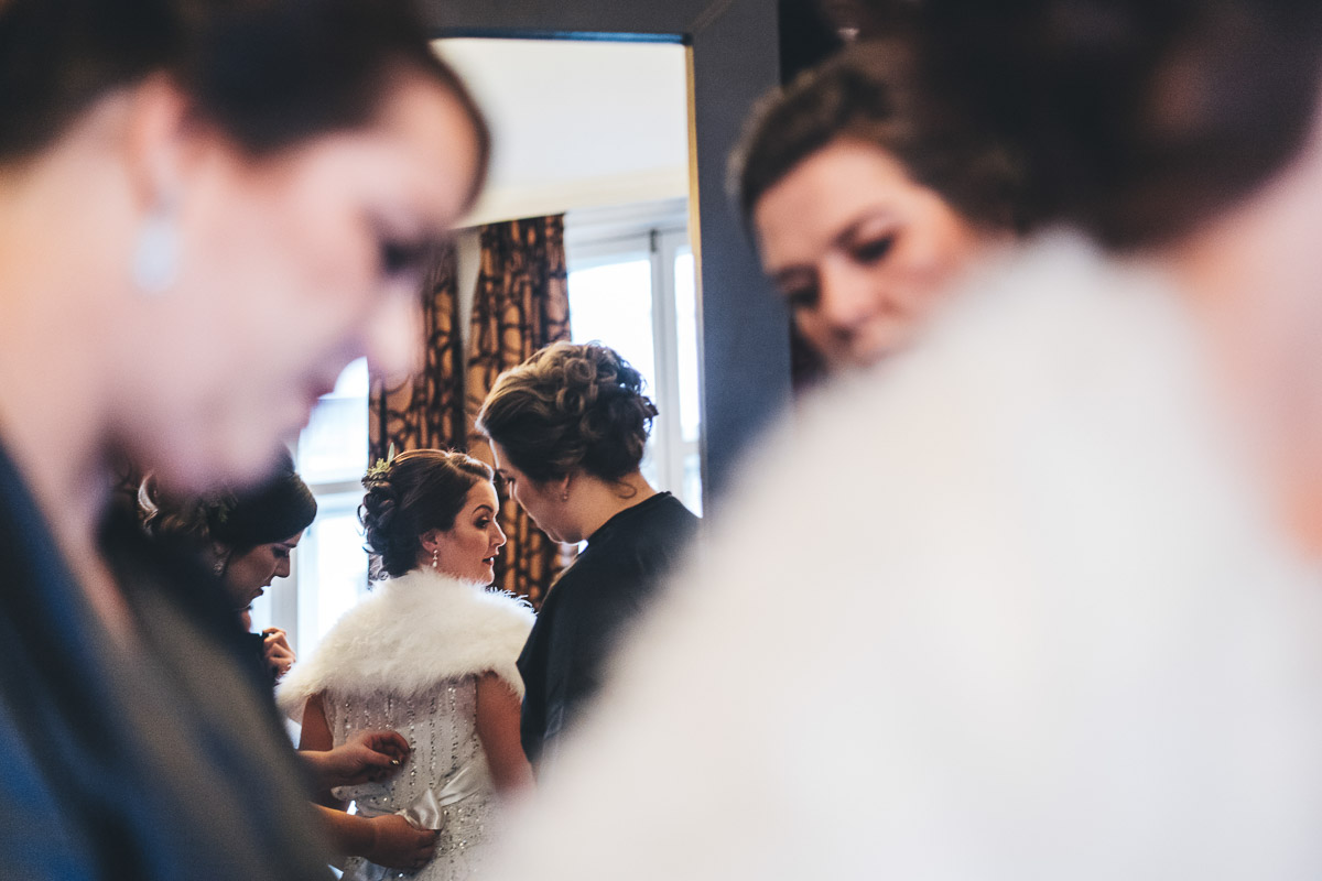 Bride getting ready in the mirror with her bridesmaids