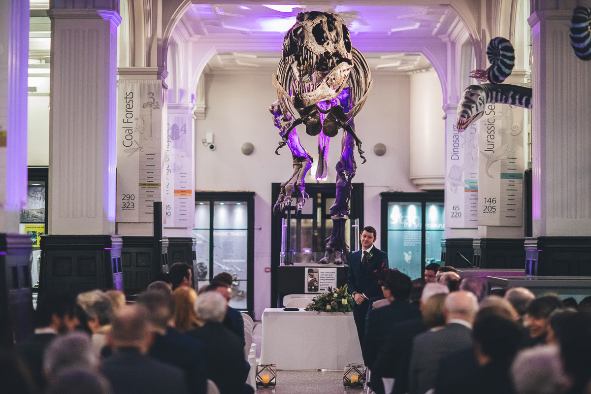 Groom waiting for bride to arrive looked over by dinosaur