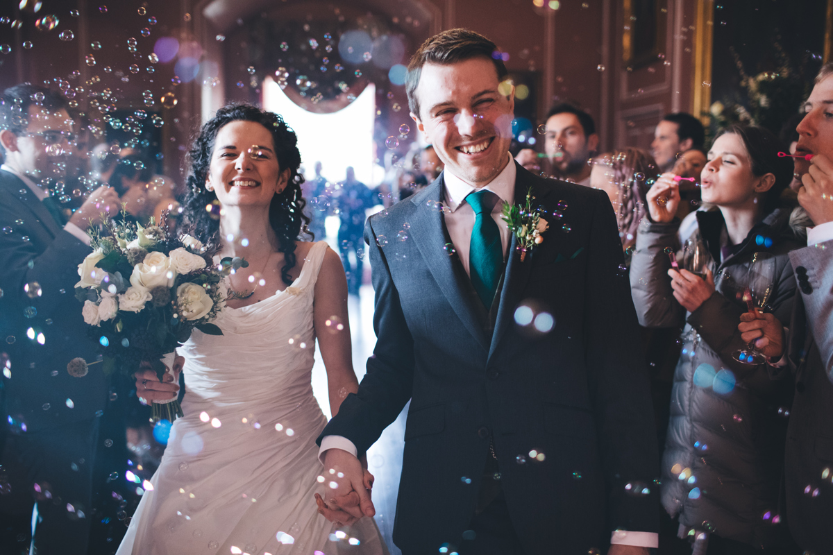 Bride and Groom walking down the aisle surrounded by bubble confetti