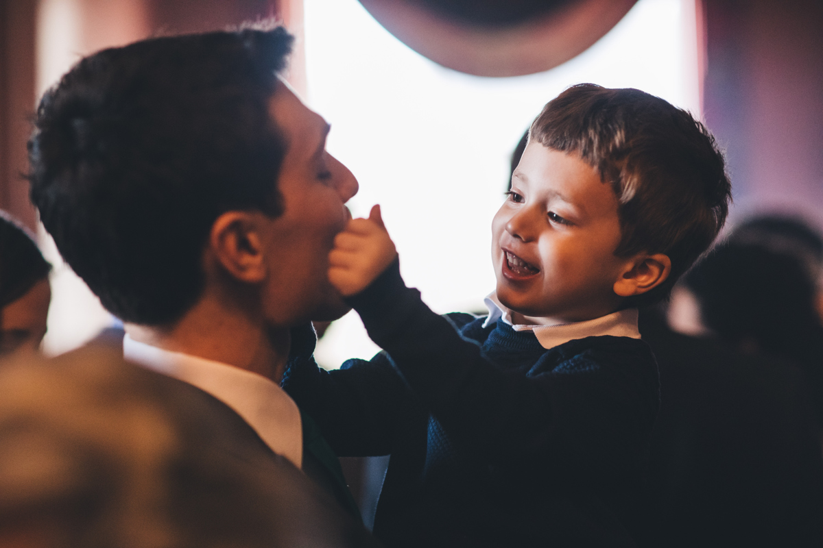 young boy being held by his father and playing with his face