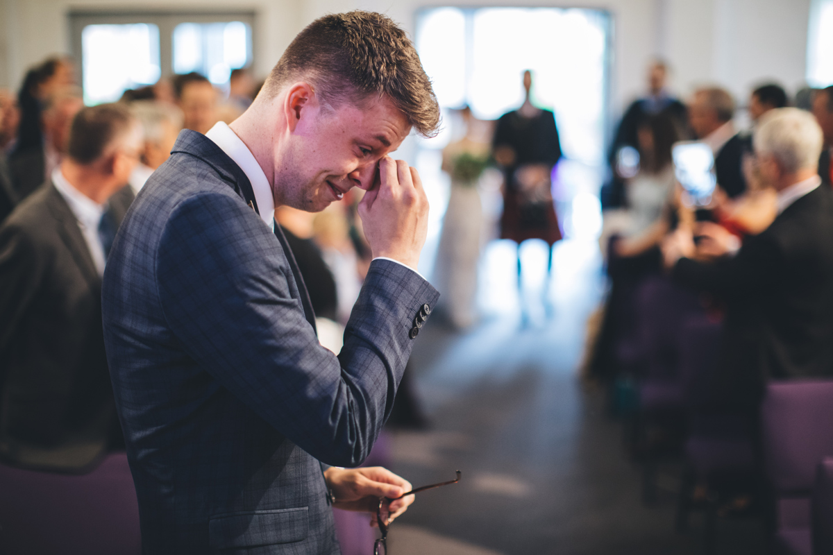Groom wiping away a tear as the bride is walked down the aisle