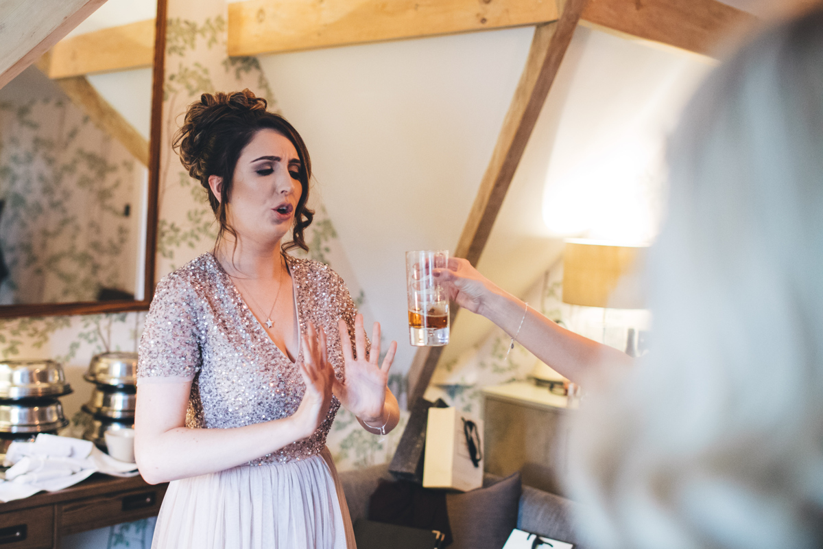 Bridesmaid with her hands in front of her saying no to a drink which is being held up in front of her