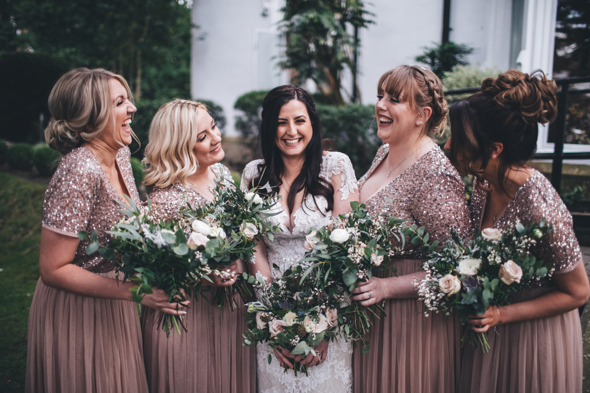 Bride with two bridesmaids on each side of her holding their bouquets in front of them