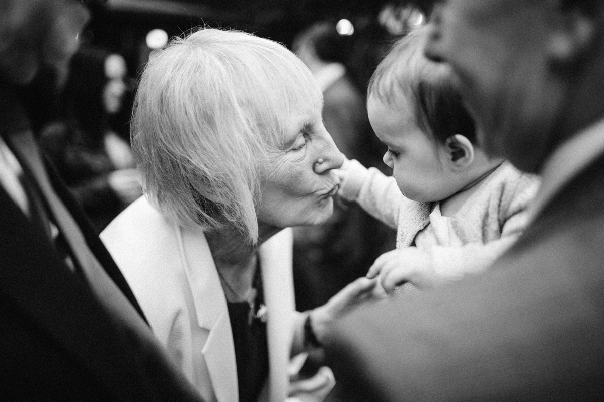 Black and white photograph of an old lady going to kiss a young child who is being held