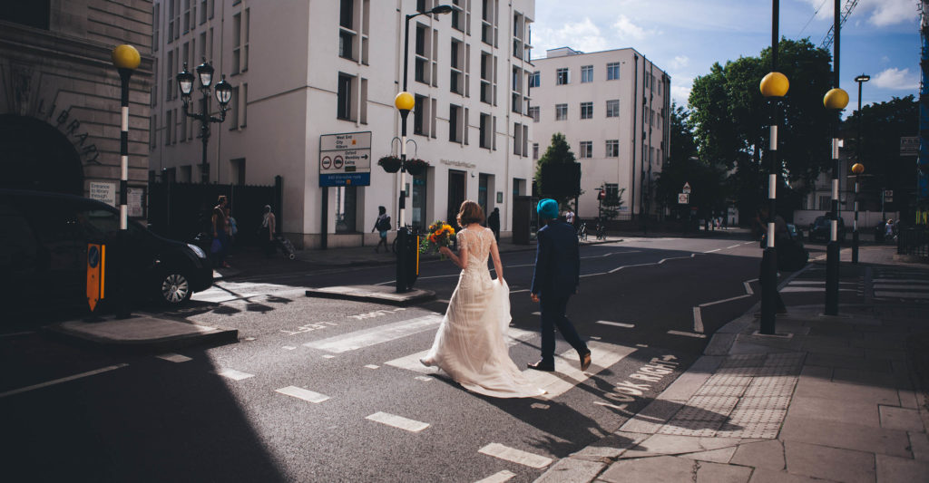 Bride and Groom walking across a pedestrian crossing in central London opposite Porchester Hall