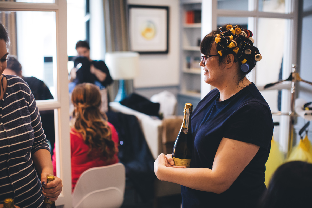 Bride with rollers in her hair with a bottle of champagne in her arms