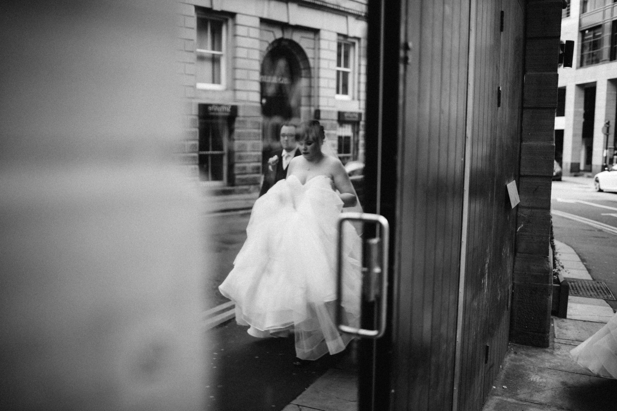 Black and white photo of the bride and groom reflected in a glass door