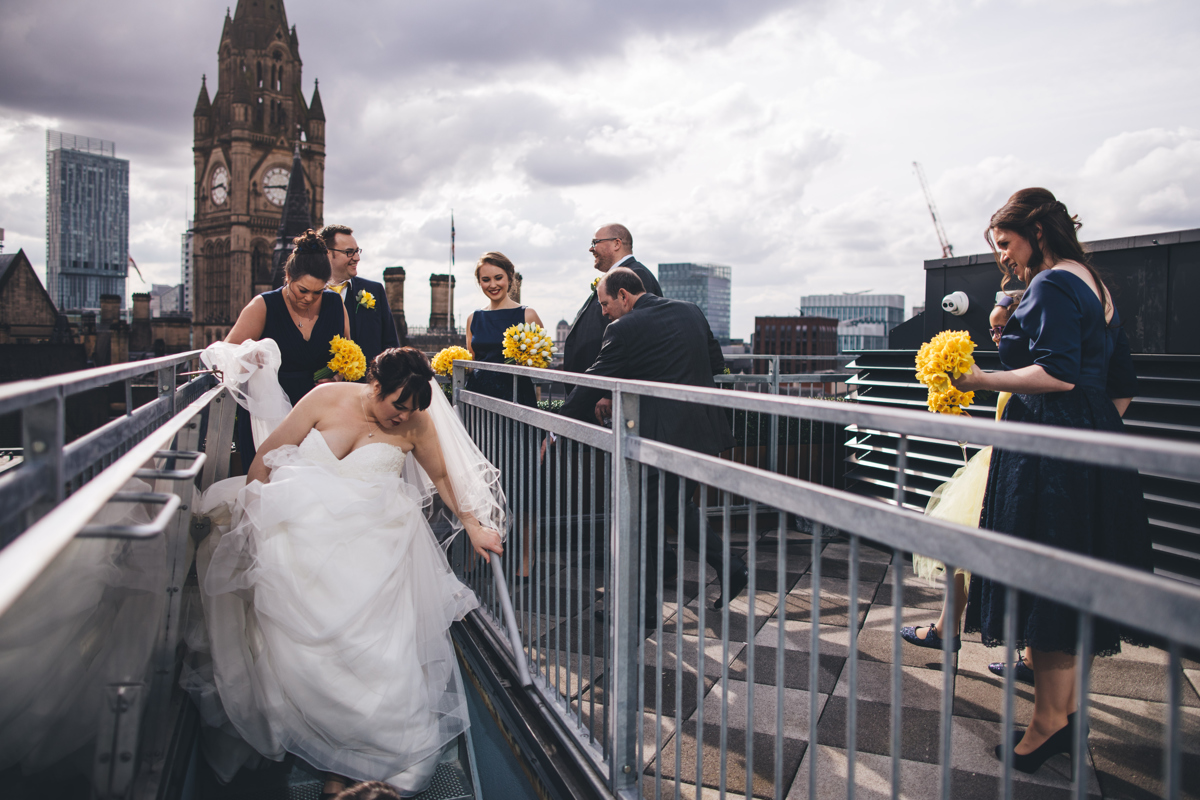 Bride walking down the stairs from the rooftop terrace at King Street Townhouse Manchester with members of the wedding party behind her