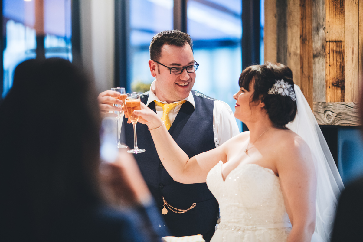 Bride and groom stood clinking champagne glasses during a toast