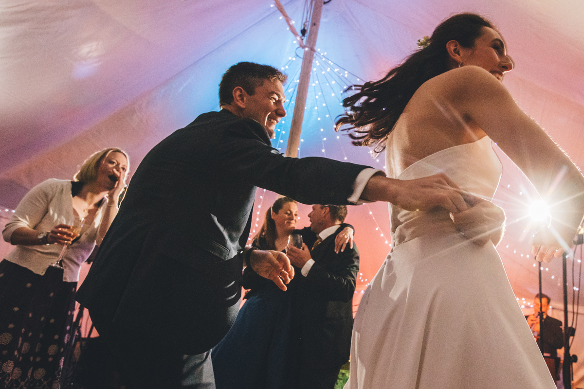 Groom spinning bride around on the dancefloor inside a marquee