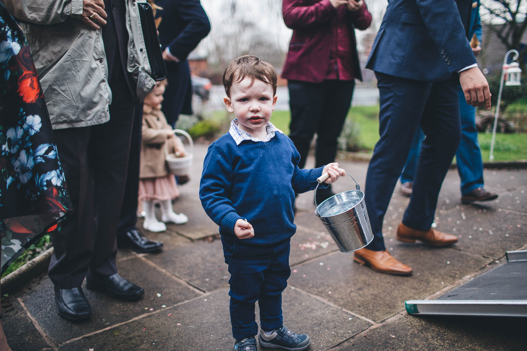 little boy holding bucket ready to throw confetti on the newly weds