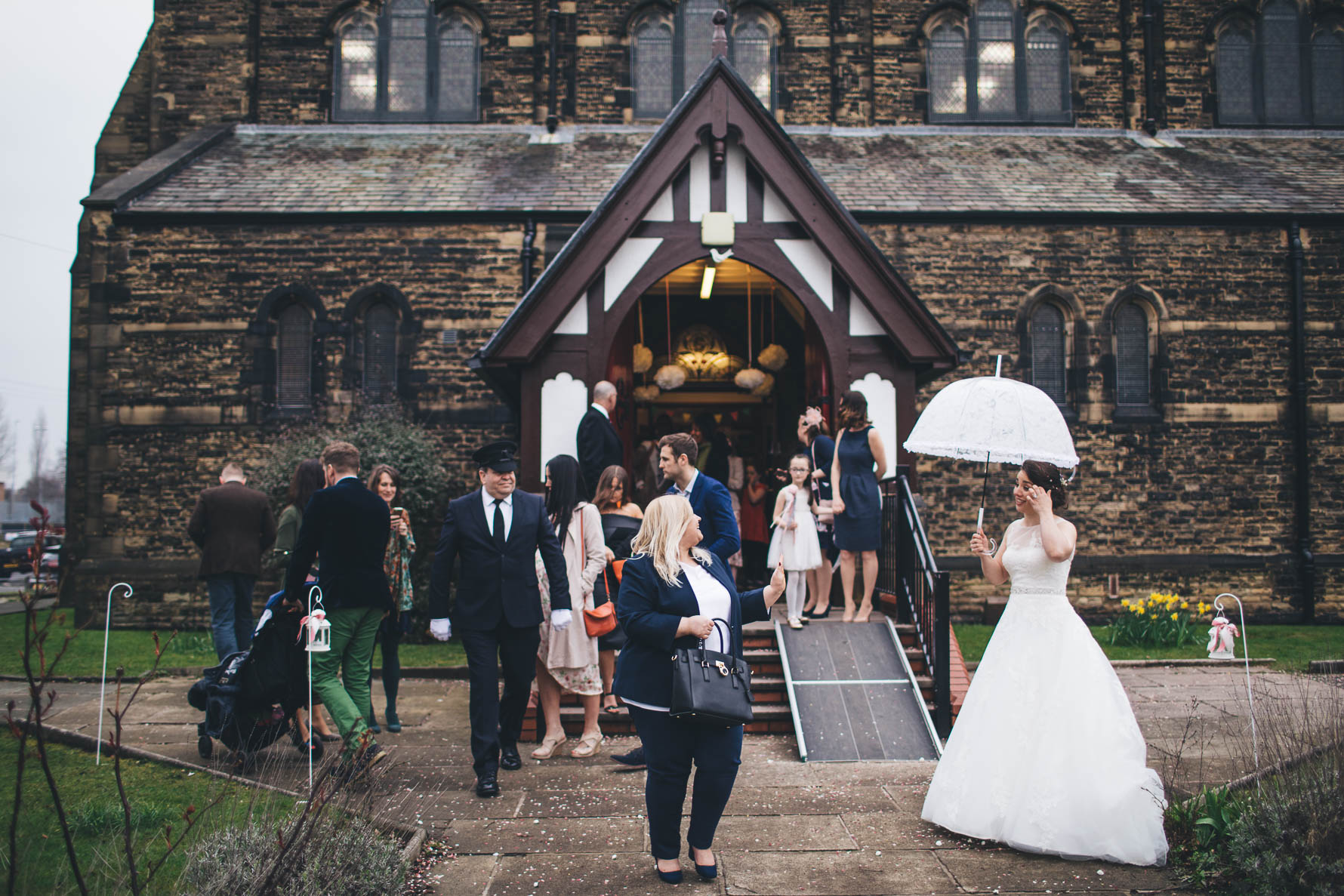 bride waits outside church with umbrella