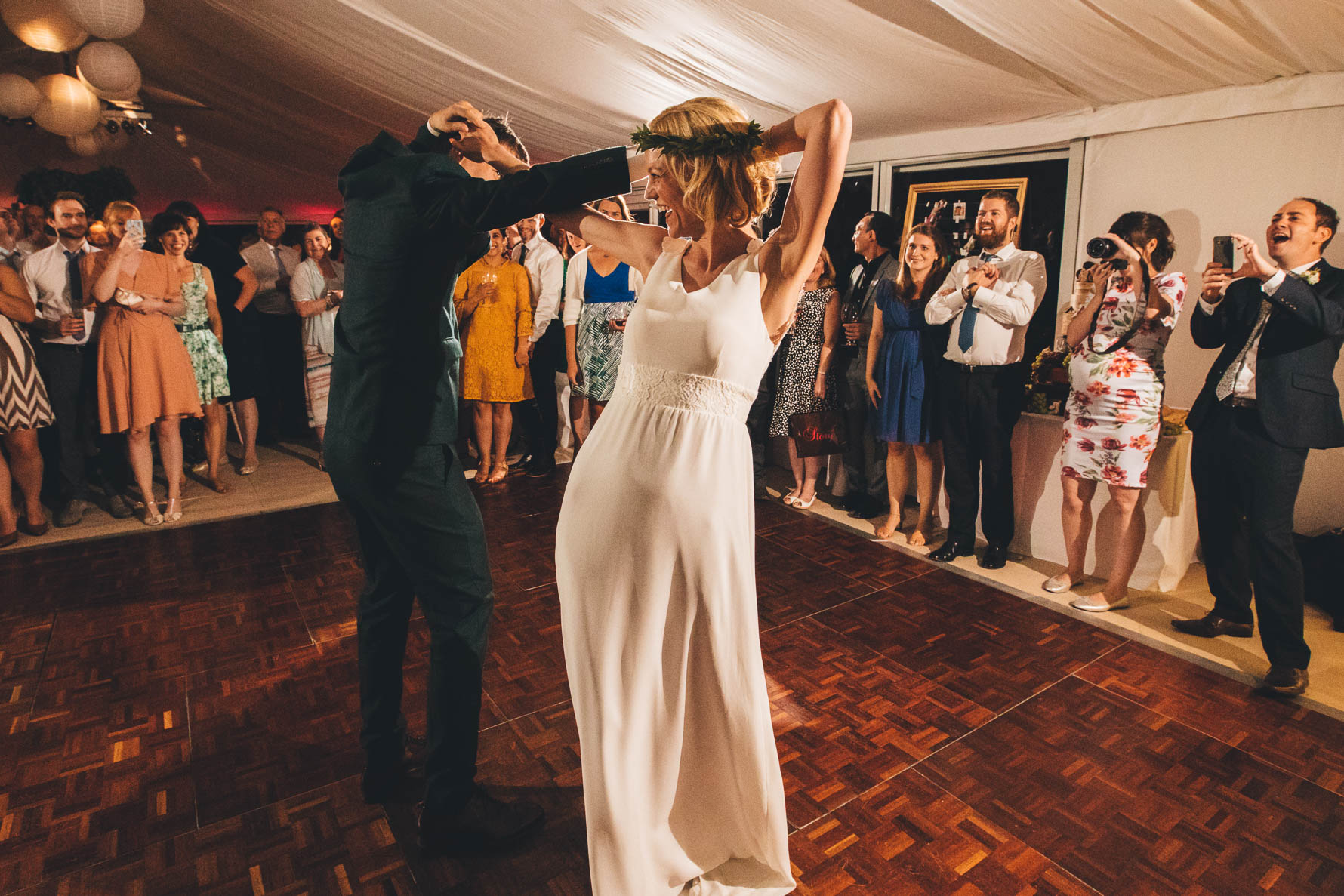 Bride and Groom on the dancefloor in a marquee during their first dance. The are holding hands but have their arms behind their heads
