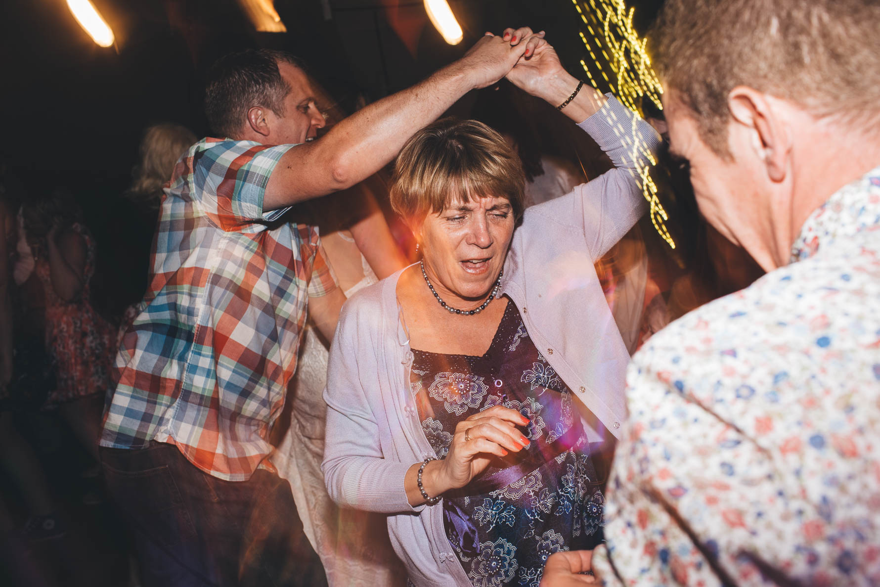 older lady dancing and being spun around with her arm in the air holding the hand of a man behind her